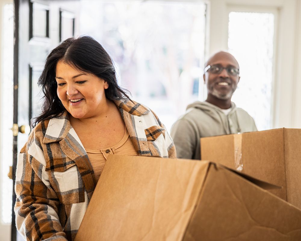 Couple Carrying Boxes into Home — Worthington, MN — Schaap Moving & Storage
