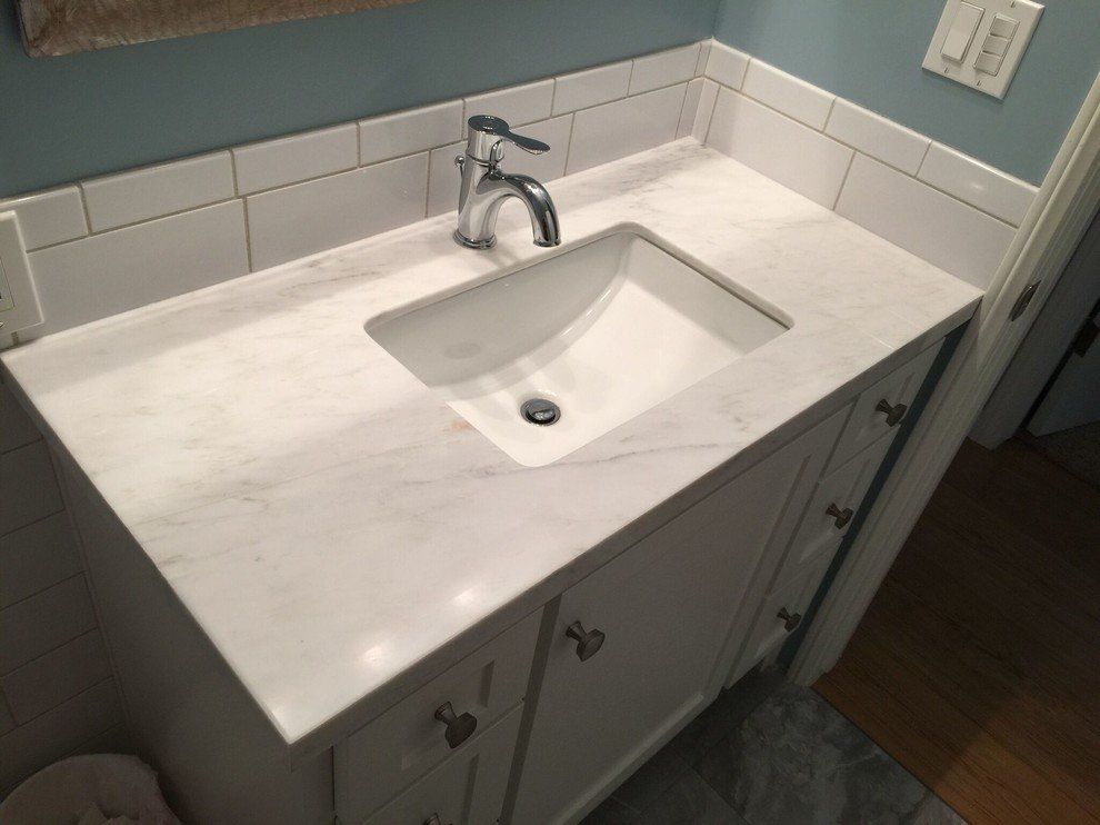 A bathroom vanity with marble countertops, a sink, and faucet on it.