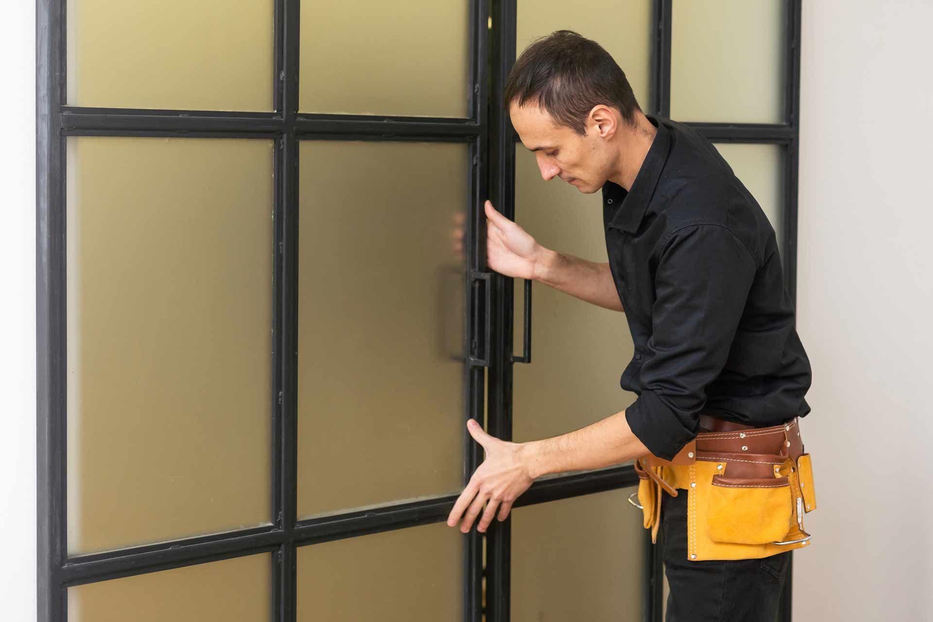 Commercial locksmith installing modern glass door lock system.