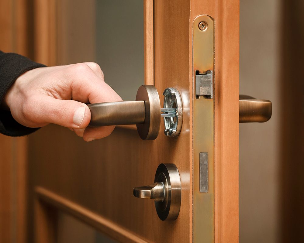 A locksmith from Shaw's Lock Service in Englewood, NJ, fixing a door lock.