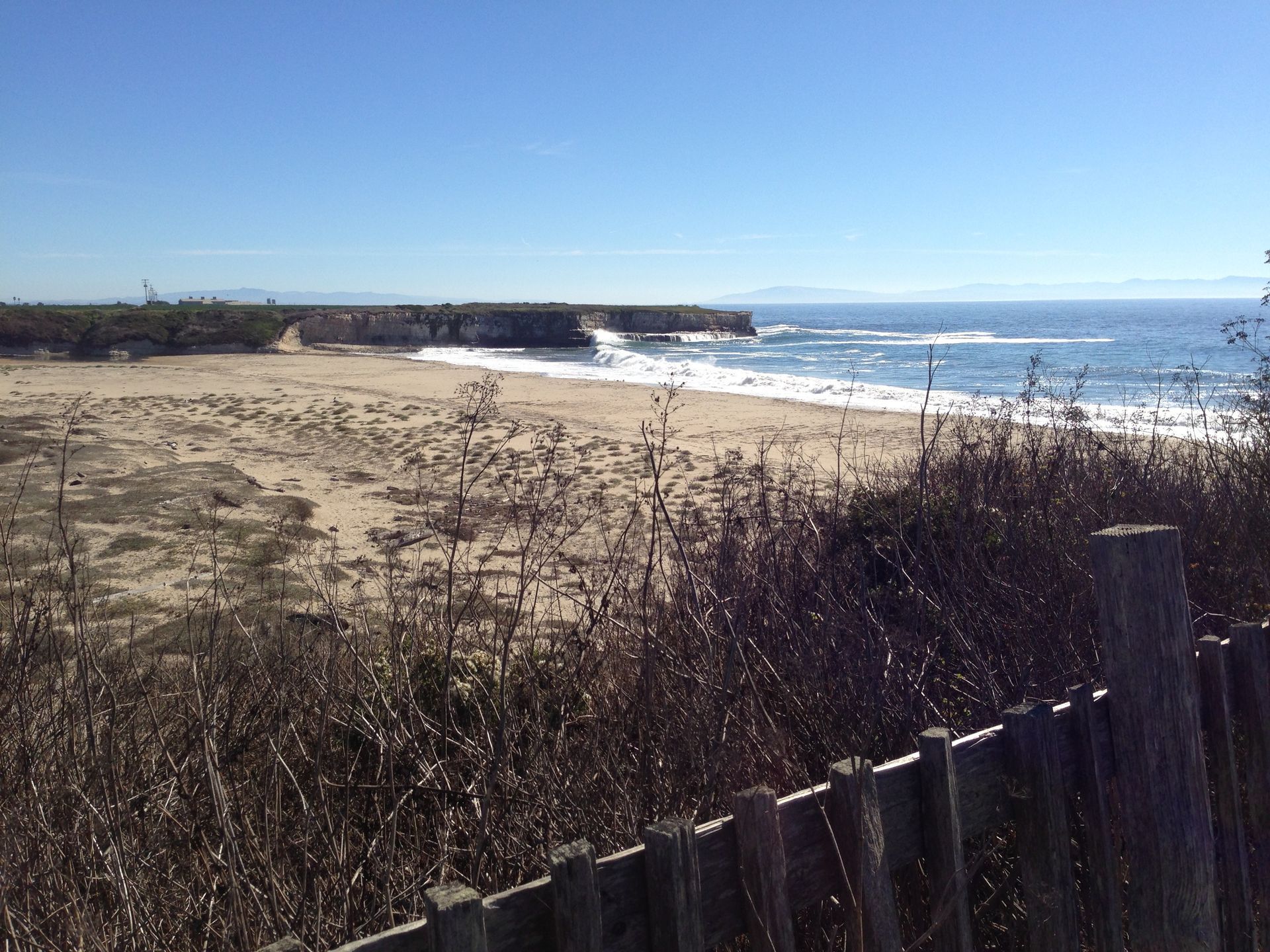 a view of a beach with a fence in the foreground