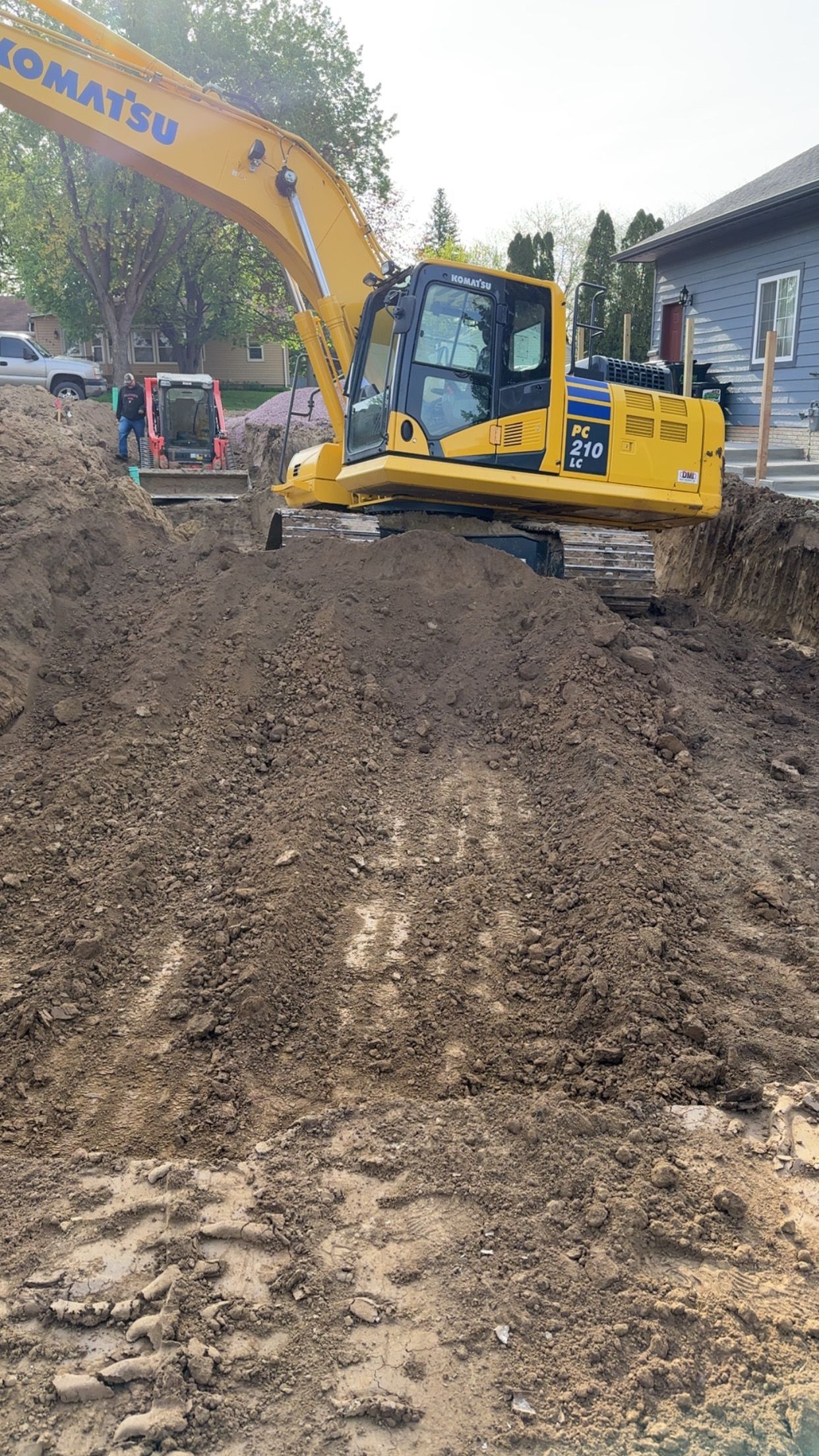 Yellow Komatsu excavator on a dirt pile, leveling the ground.