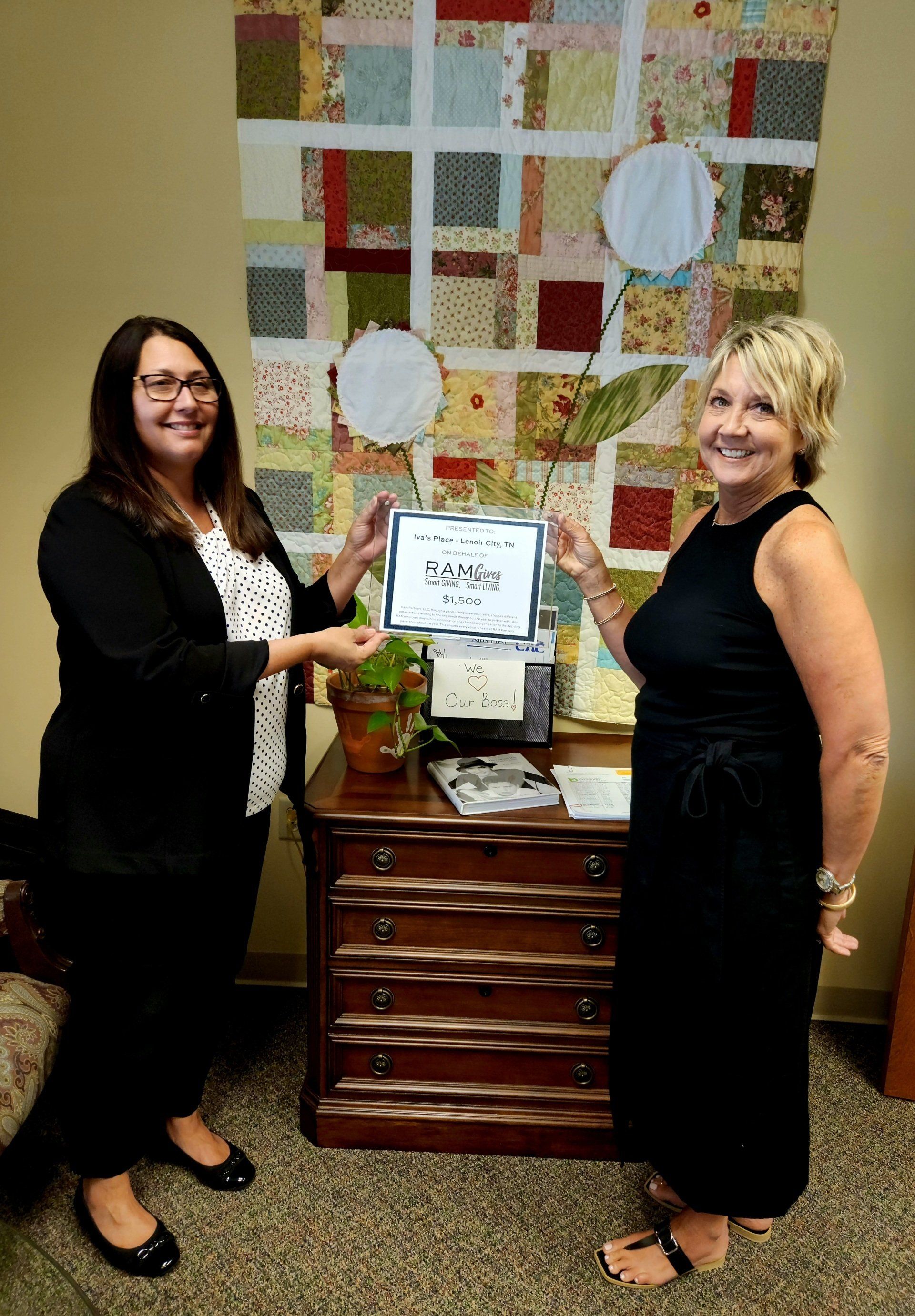Two women are standing next to each other in a room holding a certificate.