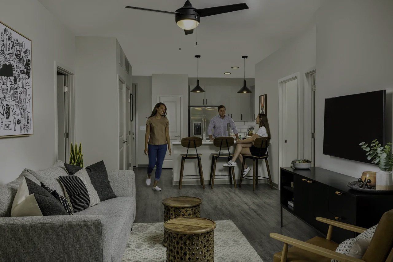 A couple is standing in a living room with a ceiling fan.
