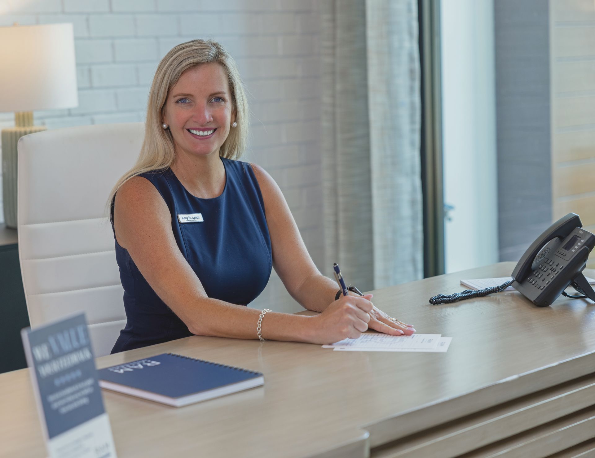 Two men are sitting at a table in a glass room talking to each other.