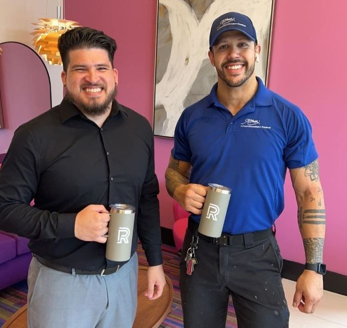 Two men are standing next to each other holding mugs with the letter r on them