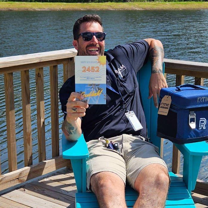 A man is sitting in a chair holding a book with the number 2452 on it