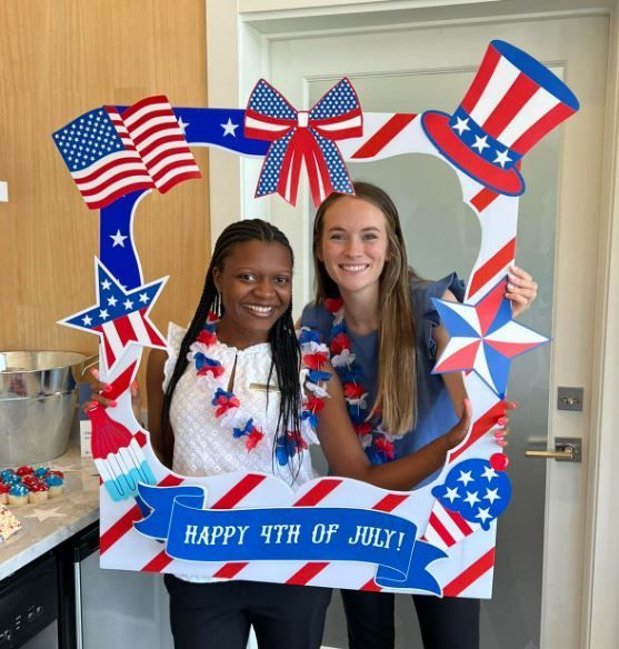 Two women holding a frame that says happy 4th of july