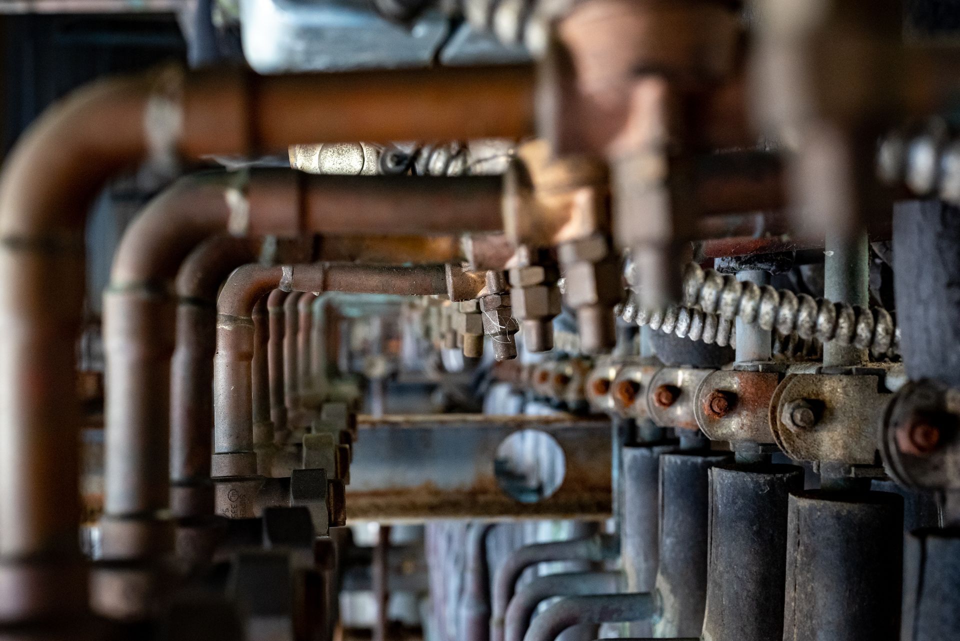 A close-up view of numerous interconnected copper pipes and industrial metal fittings inside a mechanical system.
