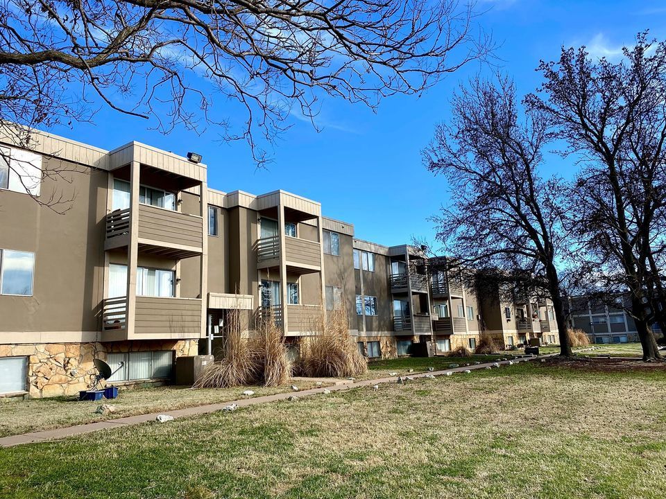 Apartment building with balconies; blue sky and leafless trees.