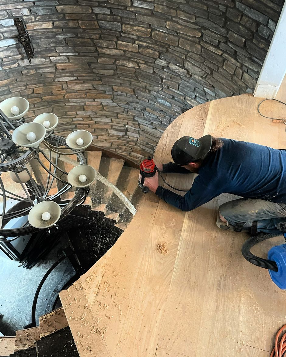 A man is working on a spiral staircase in a house.