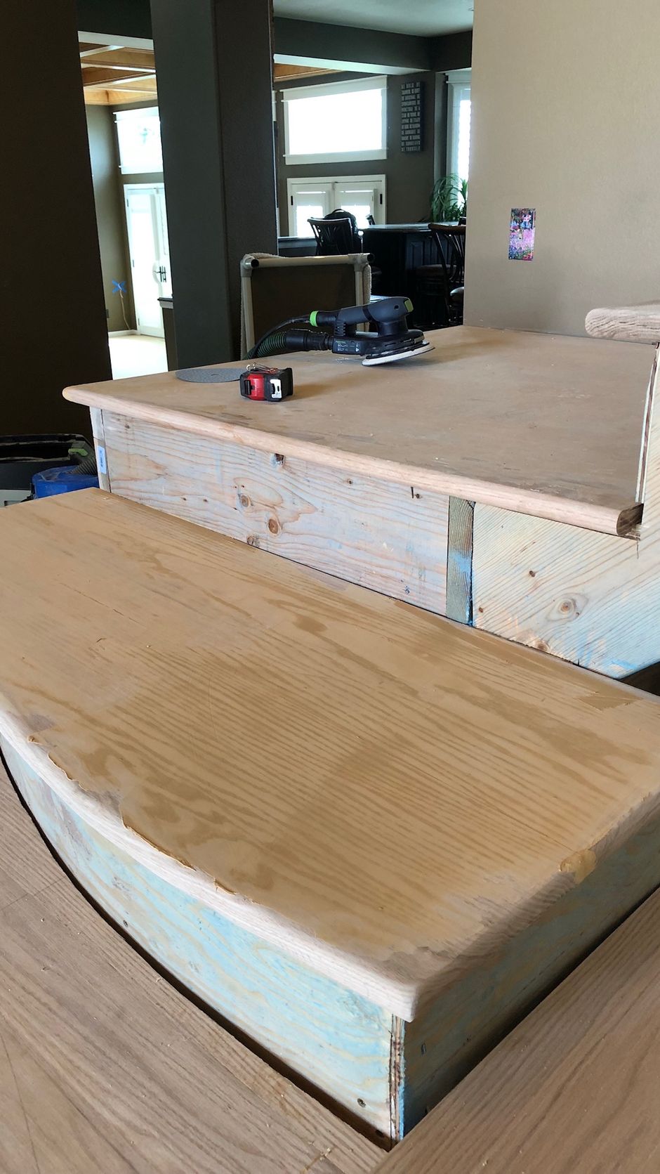 A wooden staircase is being built in a living room.