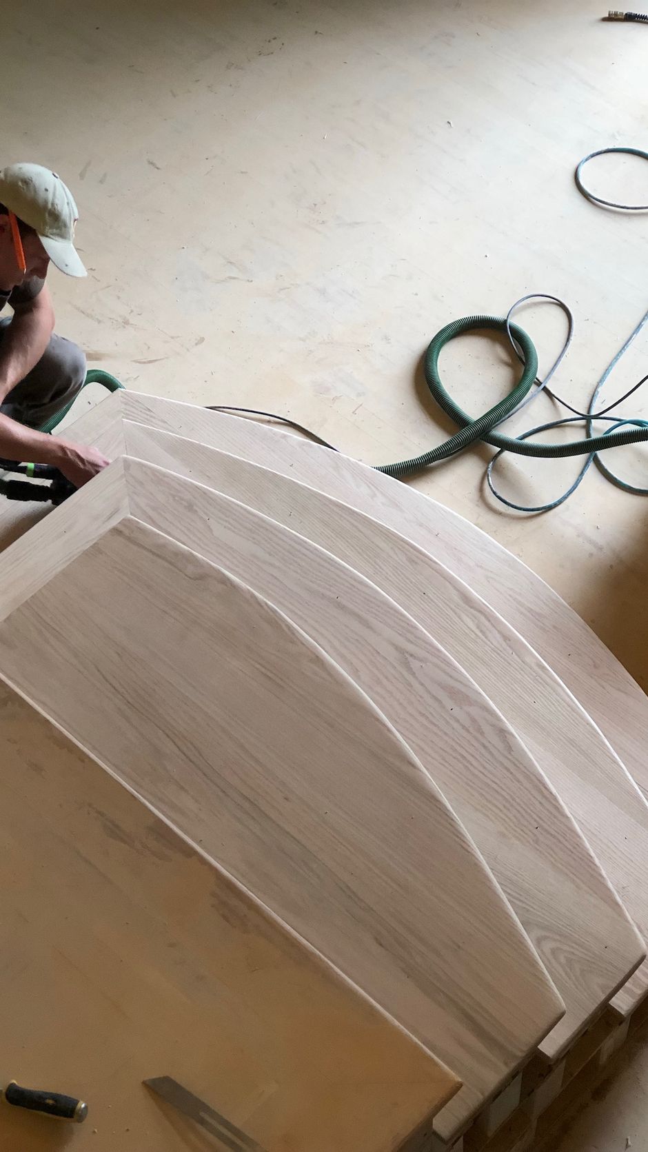 A man is working on a piece of wood on the floor