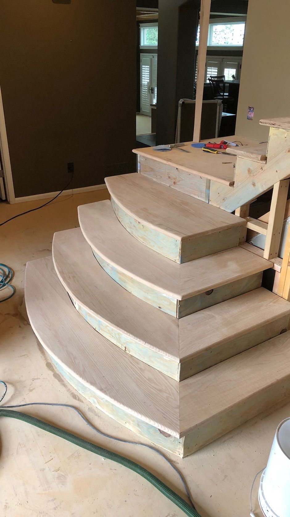 A wooden staircase is being built in a house.