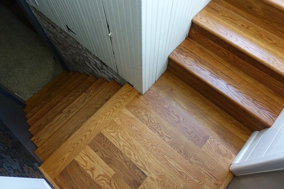 A wooden staircase with a white wall behind it