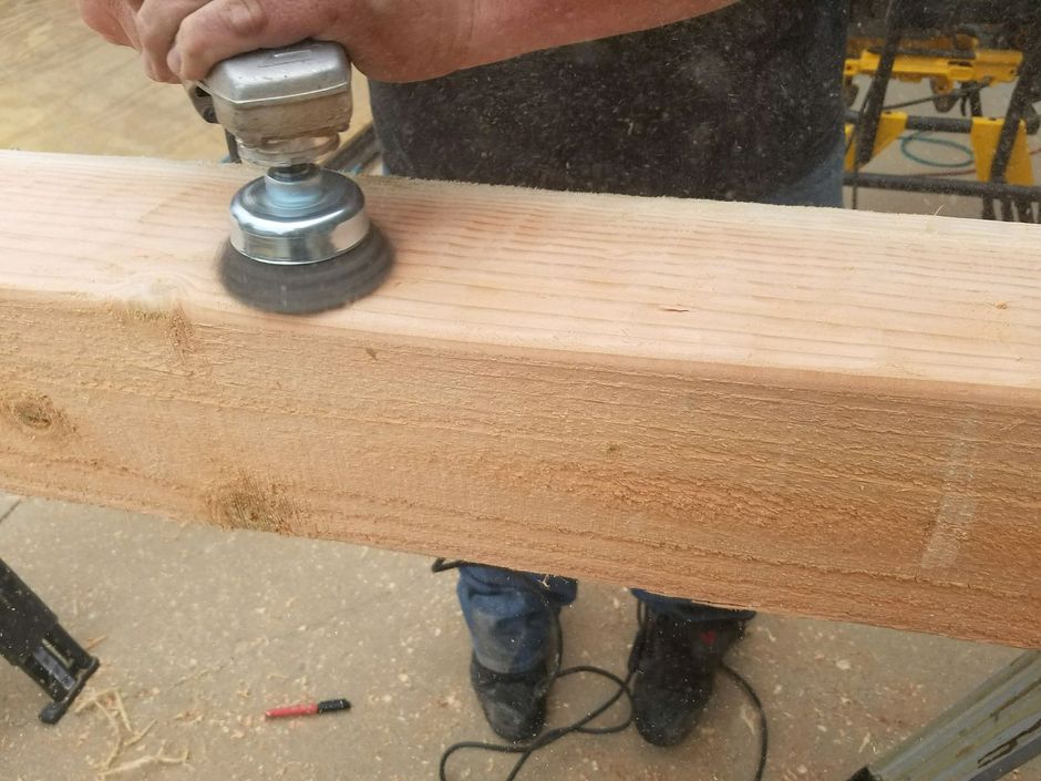 A man is sanding a piece of wood with an orbital sander.