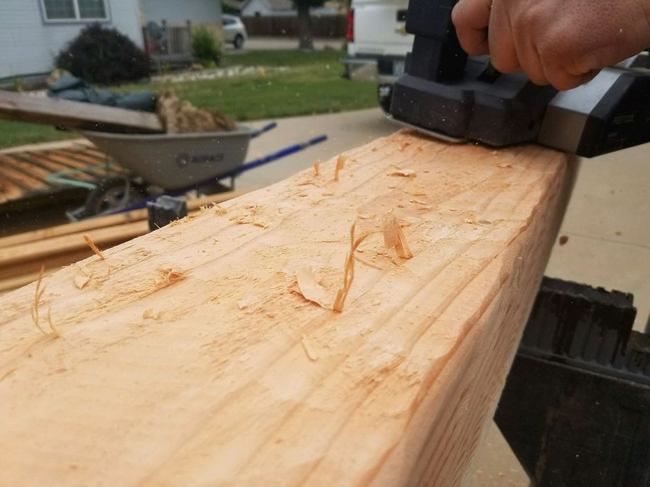 A person is using an electric plane to plane a piece of wood.