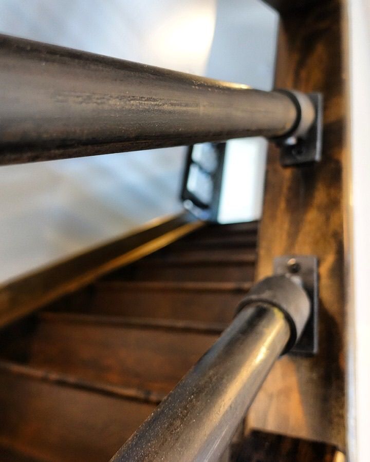 A close up of a metal railing on a wooden staircase