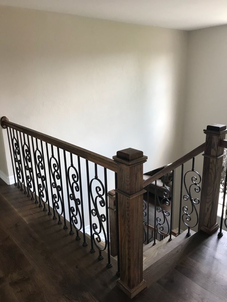 A wooden staircase with a wrought iron railing in a house.