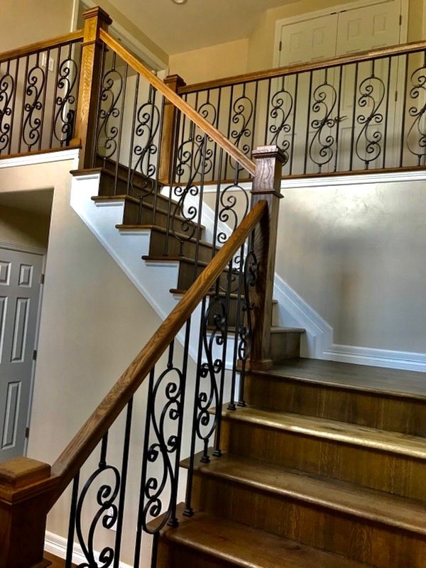 A wooden staircase with a wrought iron railing