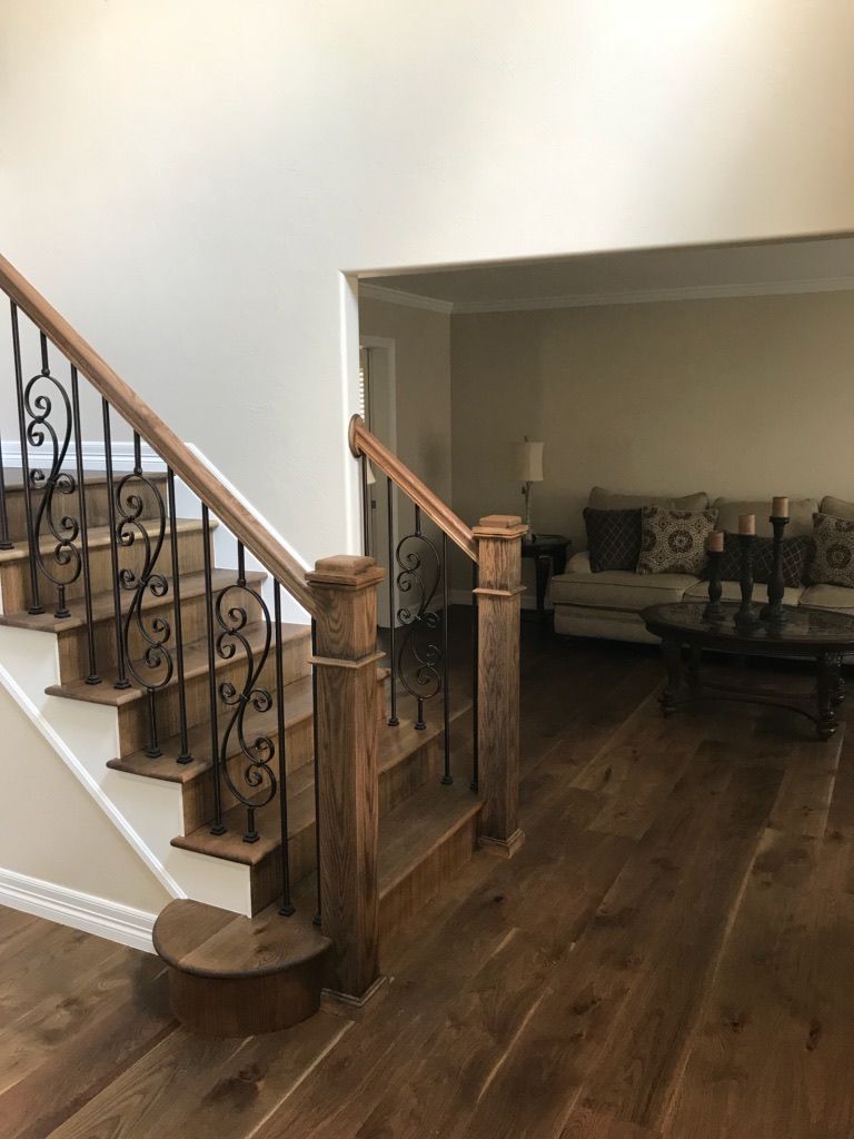 A wooden staircase with a wrought iron railing in a living room.