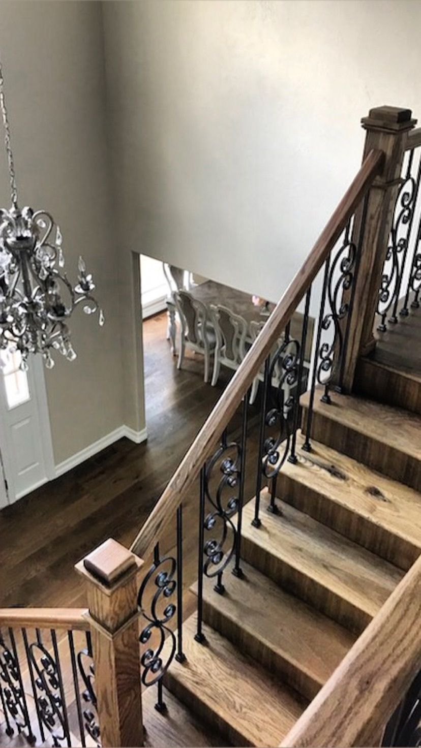 A wooden staircase with a wrought iron railing and a chandelier hanging from the ceiling.