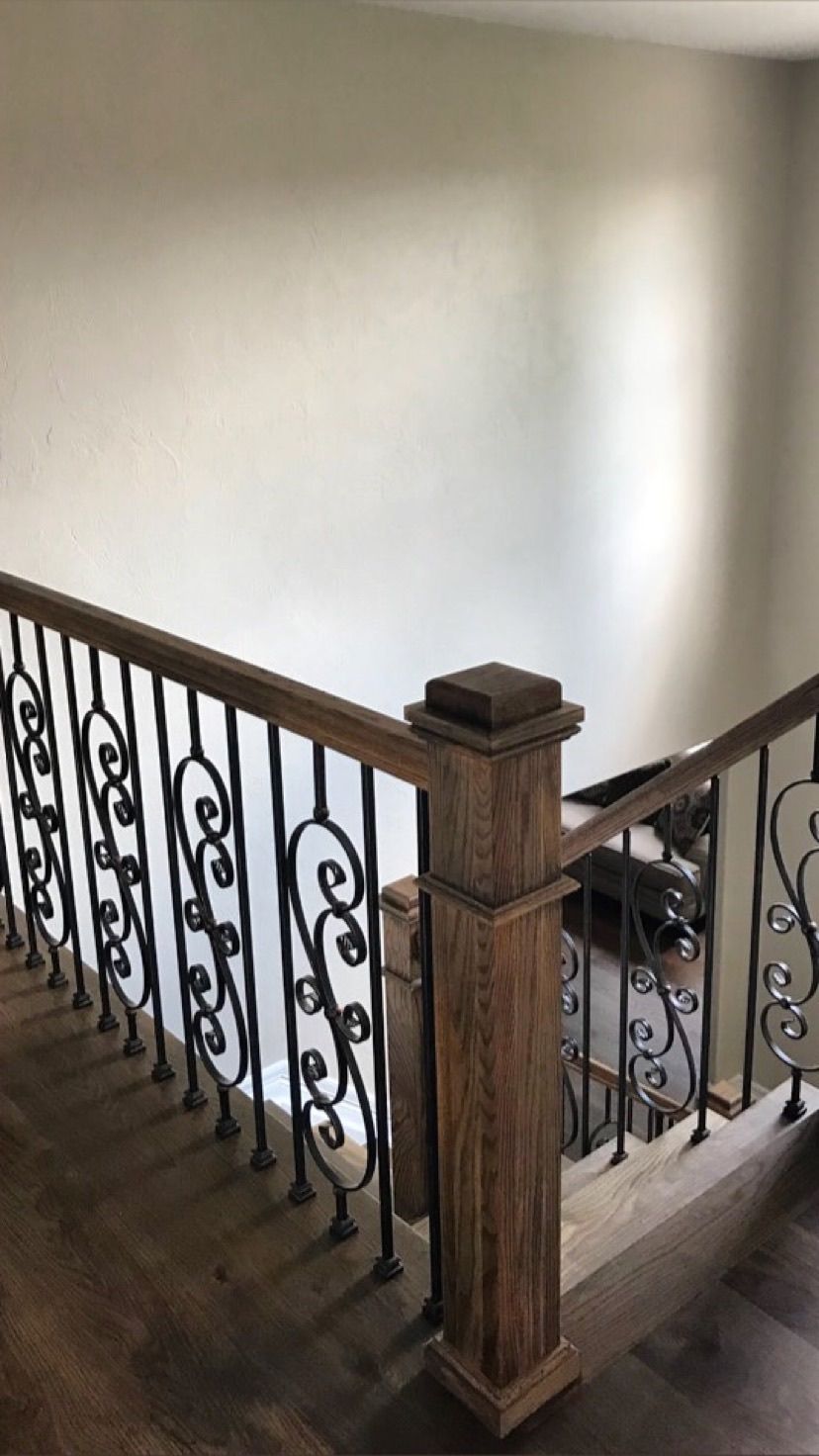 A staircase with a wooden railing and a wrought iron railing.