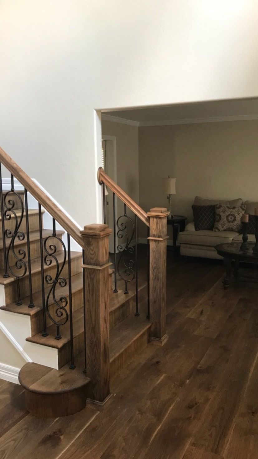 A wooden staircase with a wrought iron railing in a living room.