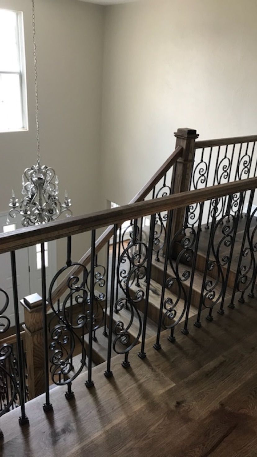 A wooden staircase with a wrought iron railing and a chandelier hanging from the ceiling.