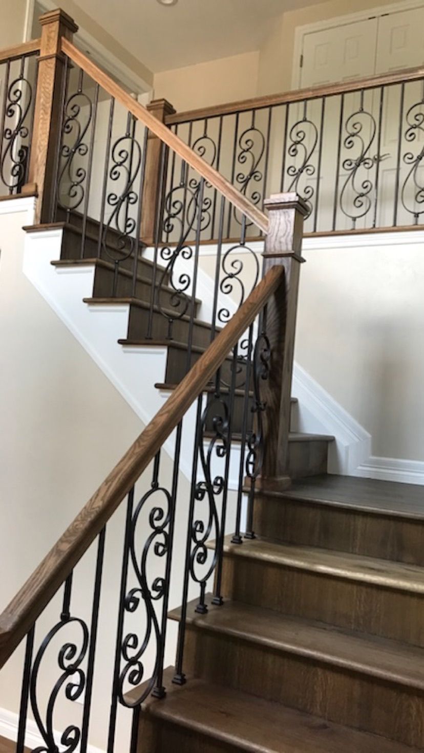 A wooden staircase with a wrought iron railing in a house.