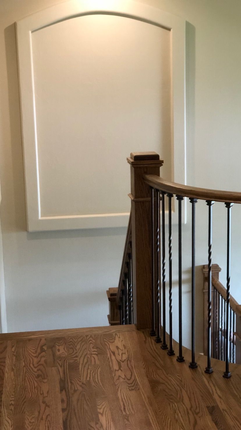 A wooden staircase with a metal railing and a white wall.