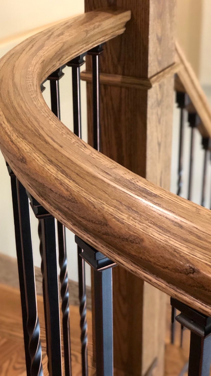 A close up of a wooden railing on a spiral staircase.