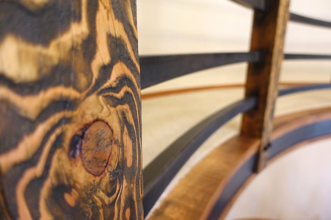 A close up of a wooden railing on a spiral staircase.