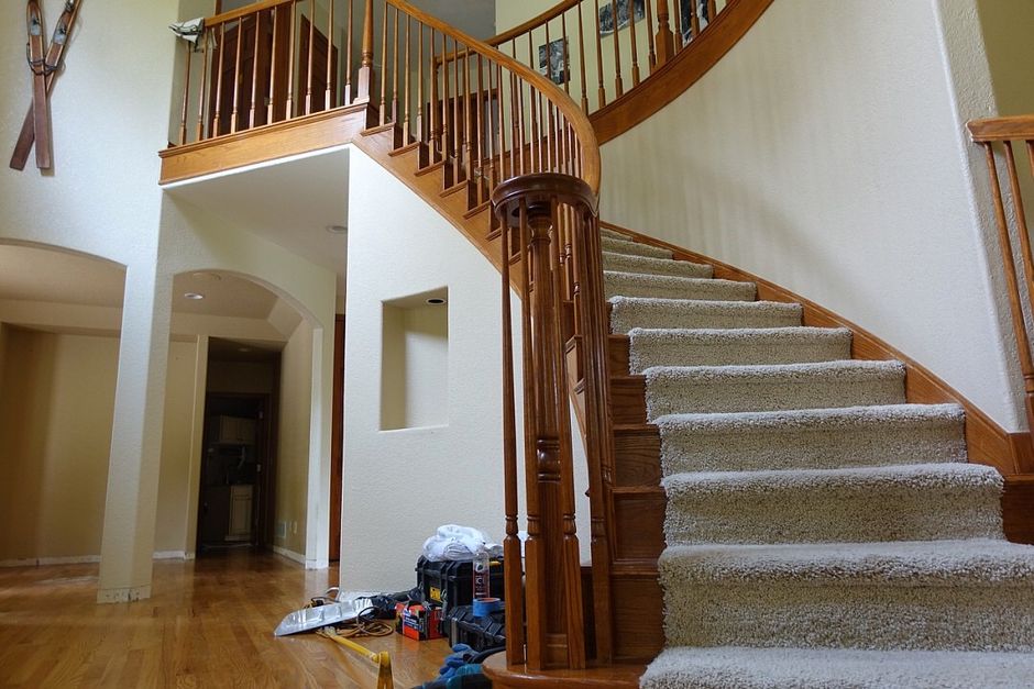 A spiral staircase in a house with a wooden railing and carpeted steps.