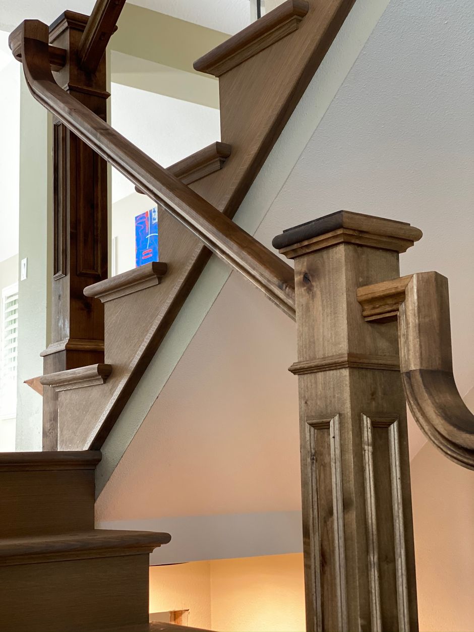 A staircase with a wooden railing and a wooden post