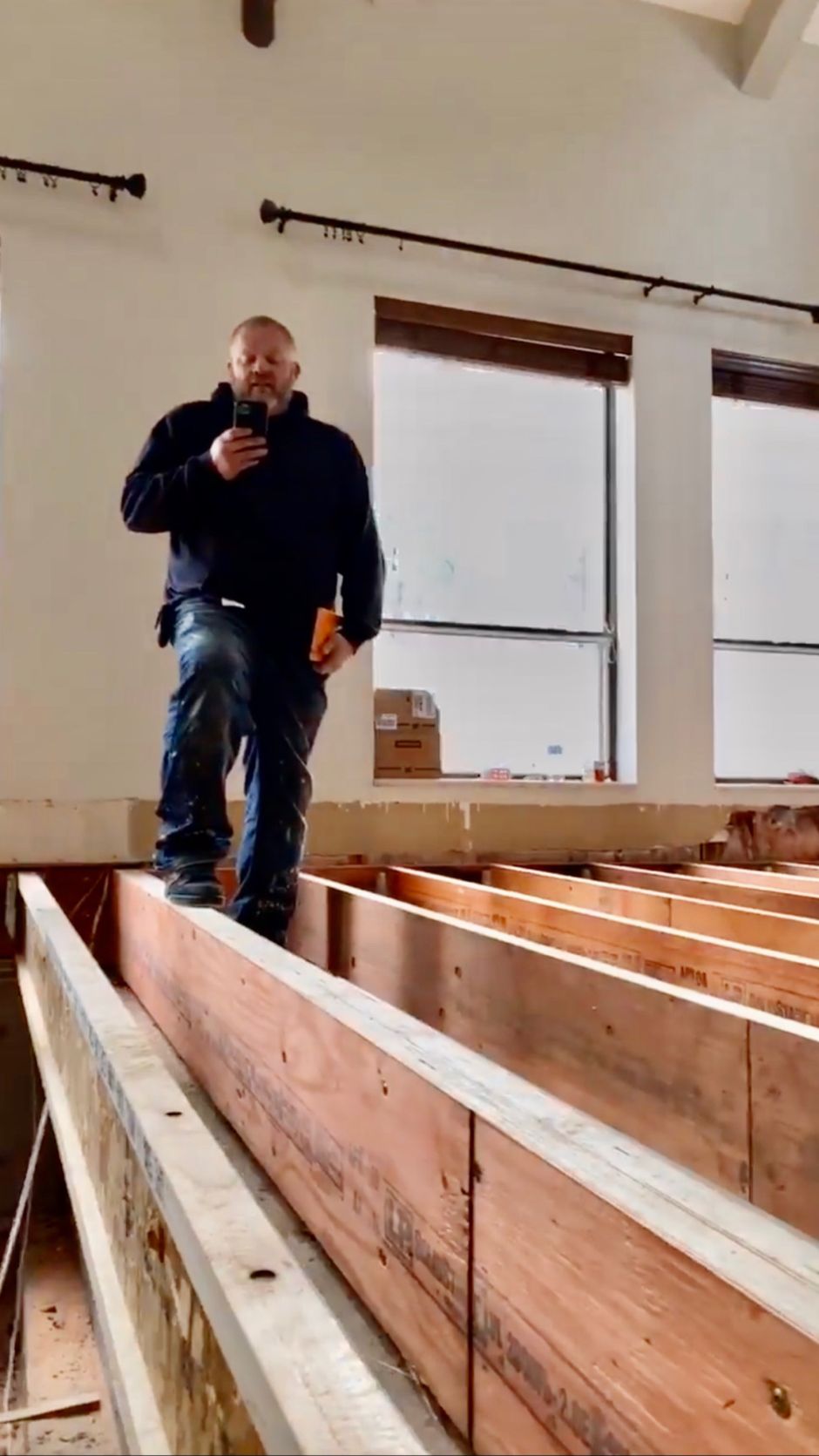 A man is standing on a wooden beam in a room.