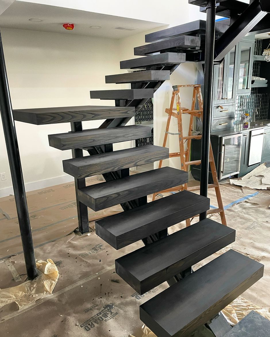 A staircase is being built in a room with a ladder in the background.