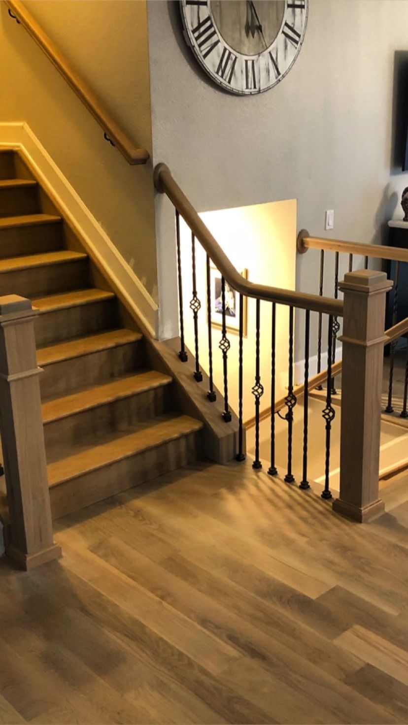 A wooden staircase with a clock on the wall above it.