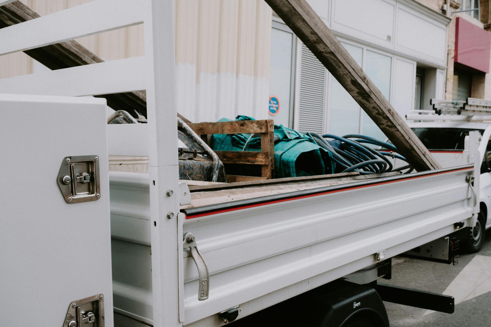 White utility truck bed filled with equipment, parked on a street.