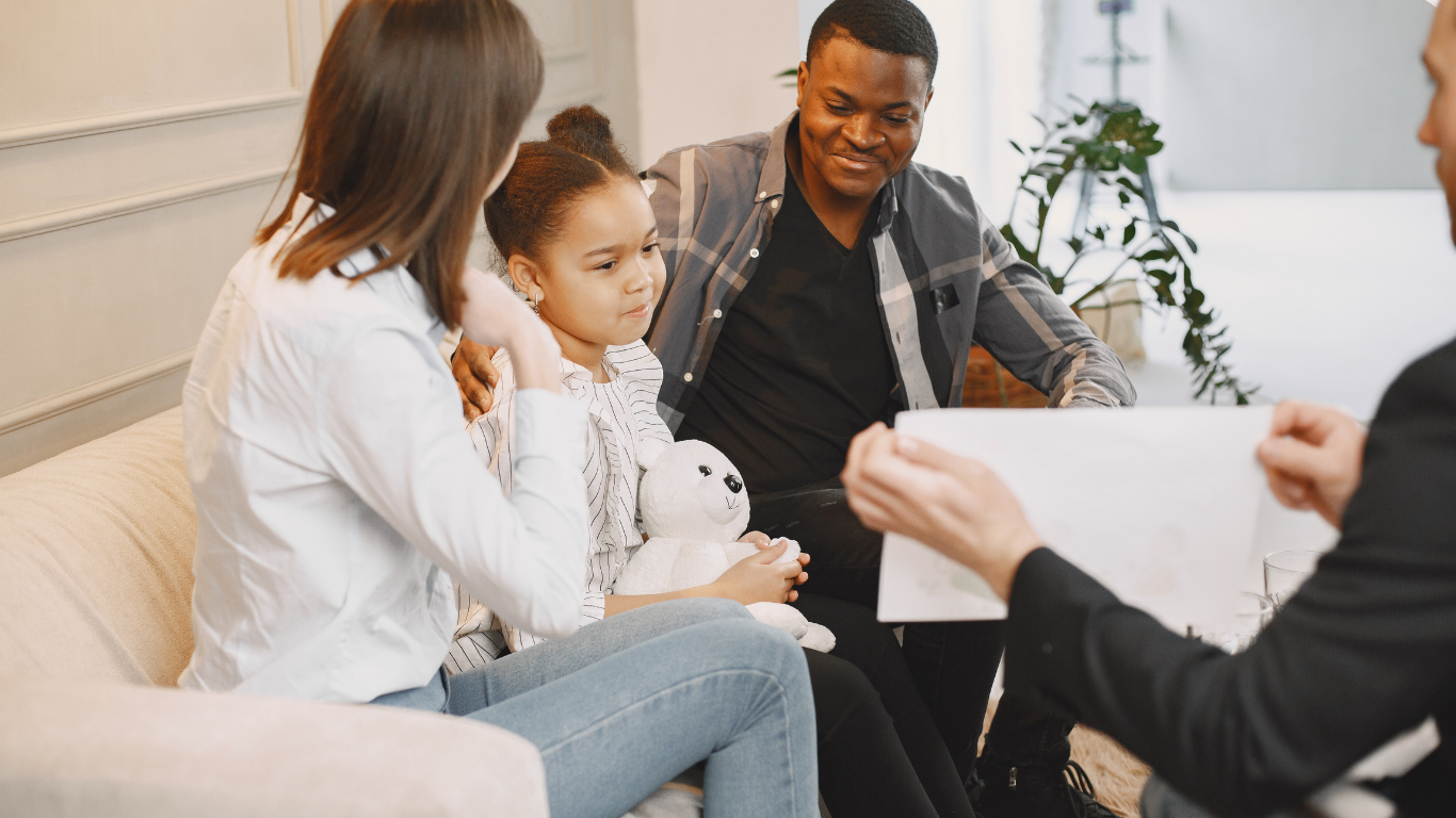 Family, child, and advisor in discussion; indoors, light-colored decor.
