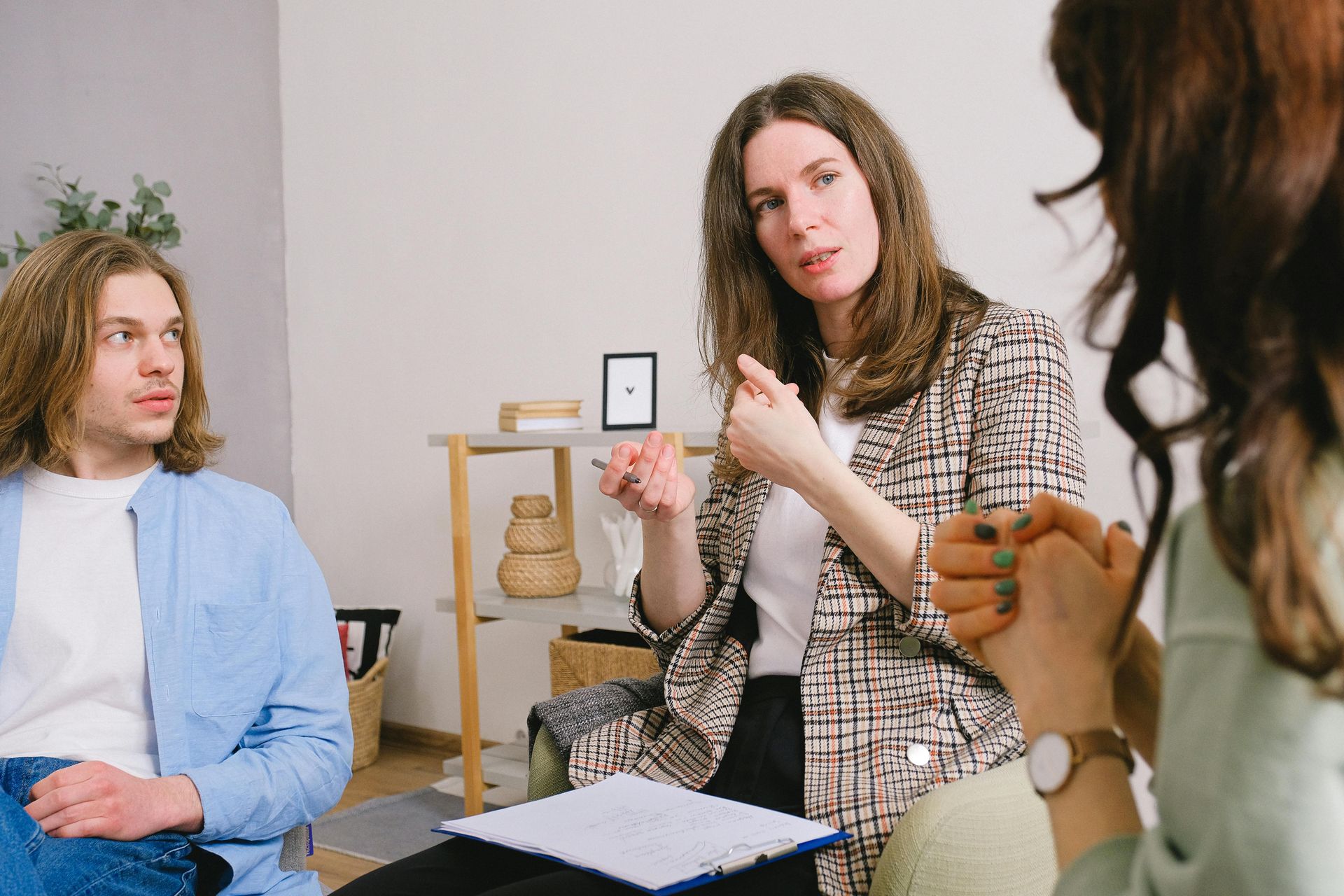 Therapist gesturing while speaking to a couple; they are seated in a counseling session.