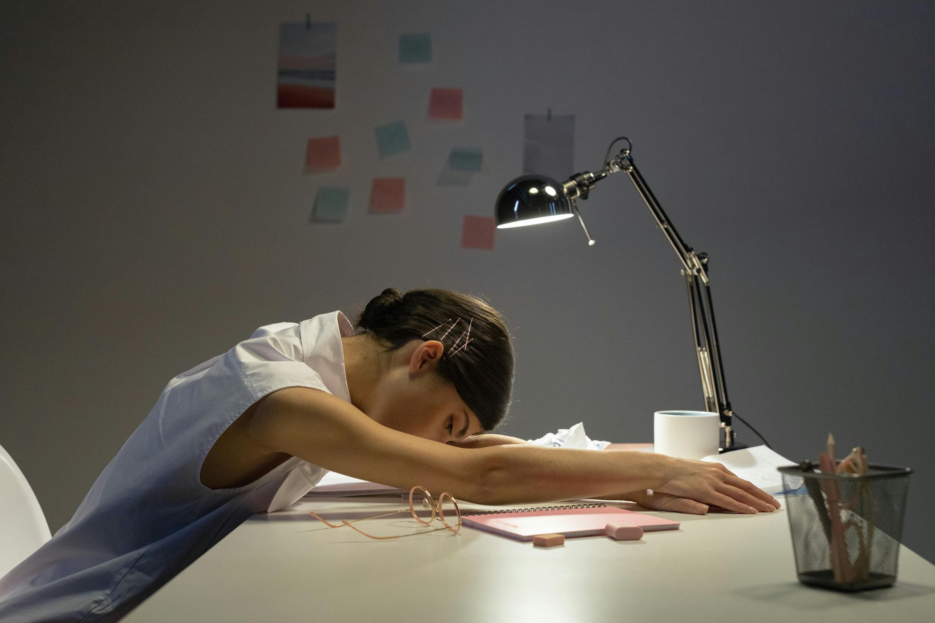 Woman in white leaning on a table, appearing sad and emotionally distressed.