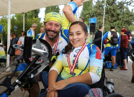 A man and a girl are sitting next to each other in a wheelchair.