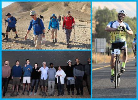 A group of people are walking in the desert and a man is riding a bike.
