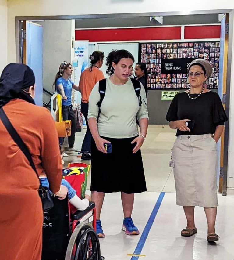 A group of people standing in a hallway including a woman in a wheelchair