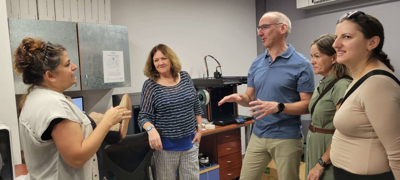 A group of people are standing in a room talking to each other.
