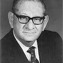 A black and white photo of a man wearing glasses and a suit and tie.