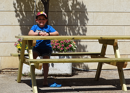 A young boy is sitting at a wooden picnic table
