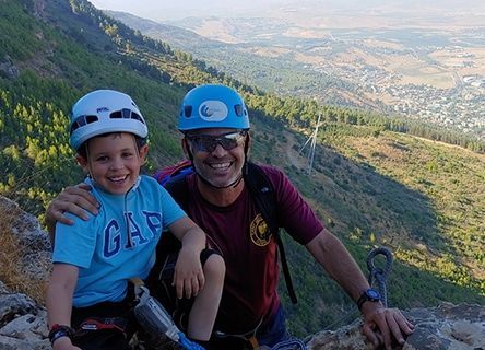 A man and a boy are posing for a picture on top of a mountain.