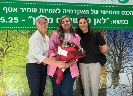 A woman in a pink jacket is holding a bouquet of flowers